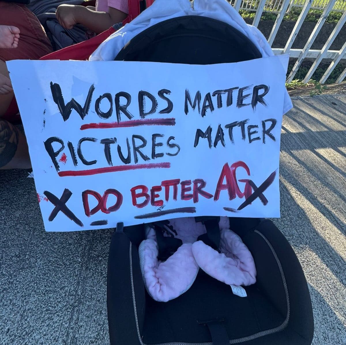Protesters gather with signs directed at attorney general